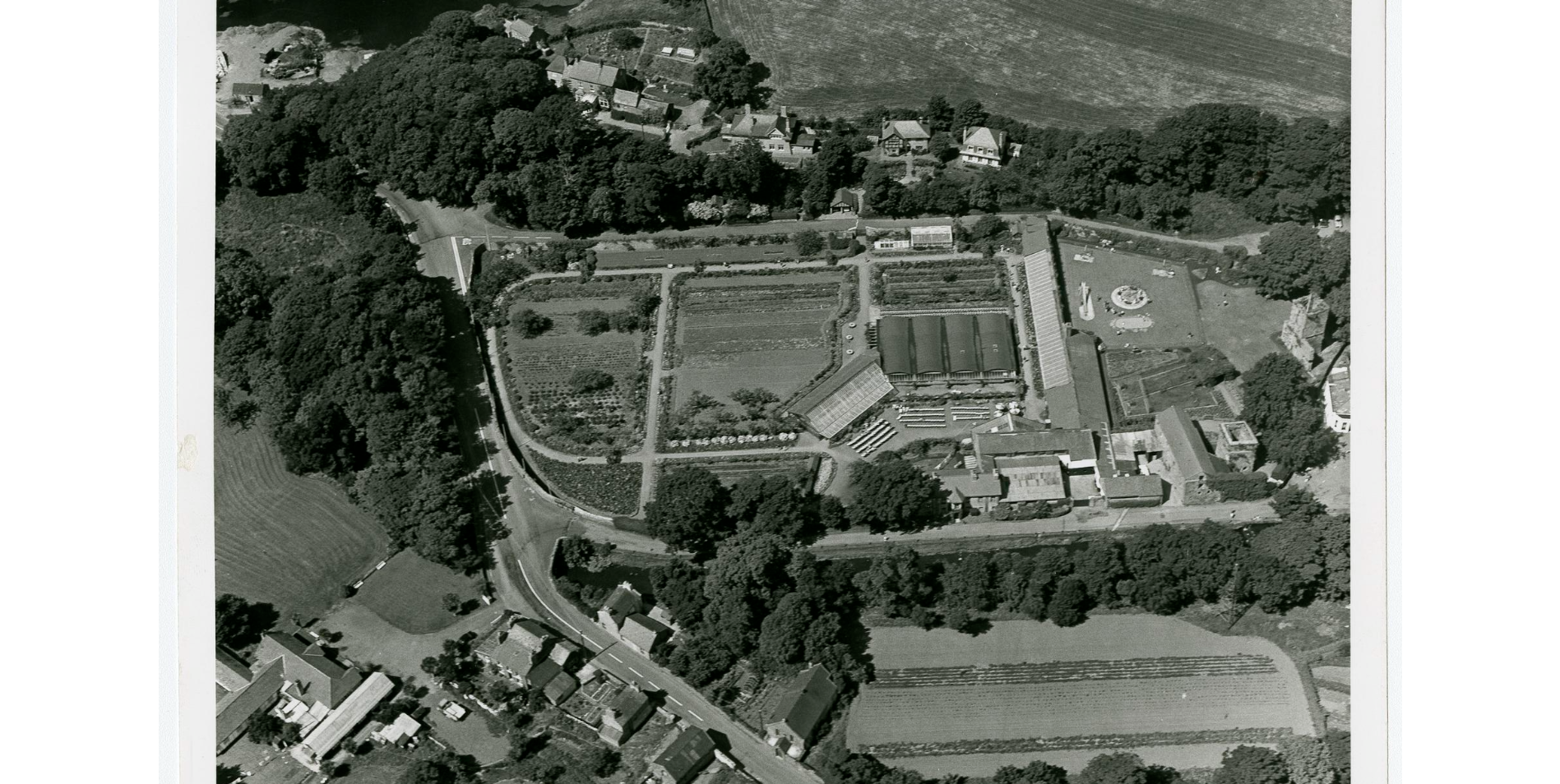 Aerial photograph, 3 March 1974: Rushen Abbey Gardens in its later tourism phase, with the Always, Beeches and Orchard row visible along the top of the frame.